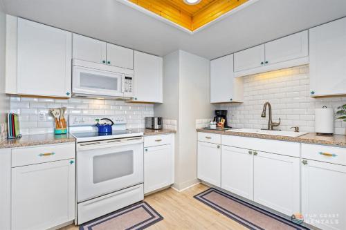 a white kitchen with white cabinets and white appliances at Beachfront 4th Floor Condo with Spectacular Beach & Ocean Views and Pool! in Bottle Island