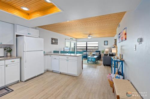 a kitchen with white appliances and a living room at Beachfront 4th Floor Condo with Spectacular Beach & Ocean Views and Pool! in Bottle Island