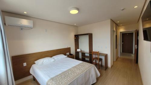 a bedroom with a bed and a table and a desk at EKT Executive Hotel in Pelotas