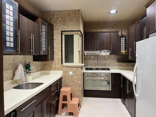 a kitchen with wooden cabinets and a sink and a refrigerator at بيت نوف للضيافة in Buraydah