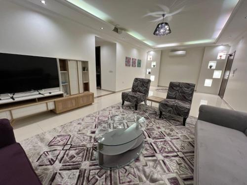 a living room with a flat screen tv and chairs at بيت نوف للضيافة in Buraydah