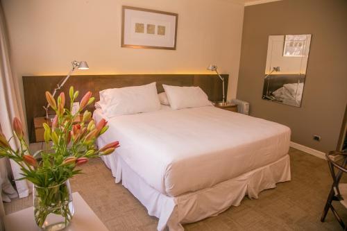 a bedroom with a white bed and a vase of flowers at Hotel Costa Real in La Serena