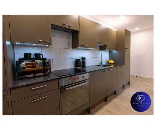 a kitchen with stainless steel appliances and brown cabinets at Modern City Centre Apartment in Exeter