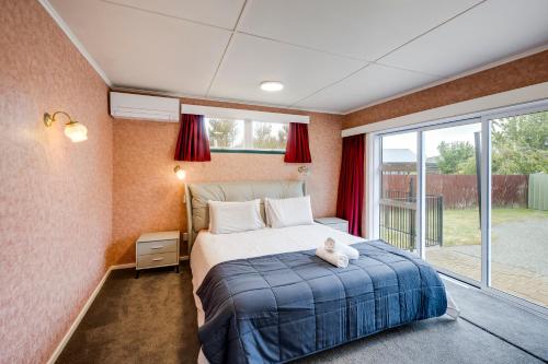 a bedroom with a bed with a teddy bear sitting on it at Mid Century Oasis - Hastings Holiday Home in Hastings