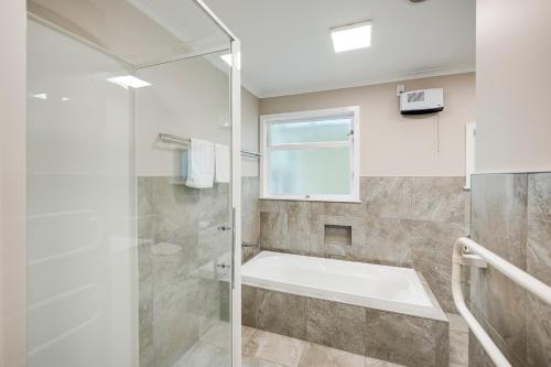 a bathroom with a shower and a bath tub at Mid Century Oasis - Hastings Holiday Home in Hastings