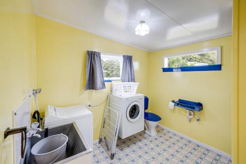a bathroom with a washing machine and a washer at Mid Century Oasis - Hastings Holiday Home in Hastings