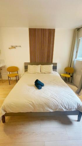 une chambre avec un grand lit blanc avec deux chaises dans l'établissement Apmt BelleVille, à Paris