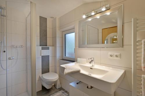 ein Badezimmer mit einem Waschbecken, einem WC und einem Spiegel in der Unterkunft Landhaus Fuchs in Walchsee