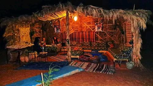 una habitación con una gran cabaña de paja con gente en ella en Camp Abrib merzouga, en Merzouga