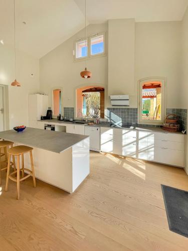 une grande cuisine avec des armoires blanches et une table dans l'établissement Grande maison de famille rénovée, vue sur Sainte Victoire, à Venelles