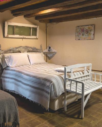 a white bed with a bench in a bedroom at Posada Niña Juana in Villa Dolores