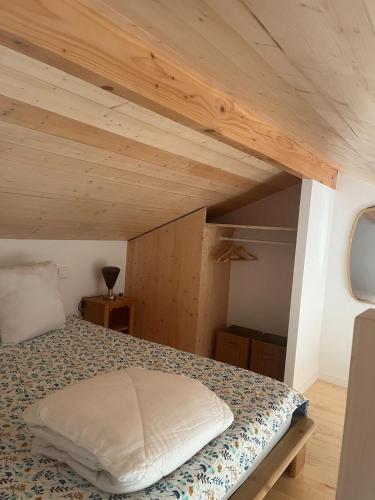 a bed in a room with a wooden ceiling at Charmant logis entre lac et montagnes in Doussard