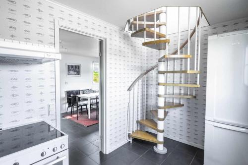 a spiral staircase in a kitchen with a dining room at Coastal gem with beach, wooden sauna & canoes in Bjästa