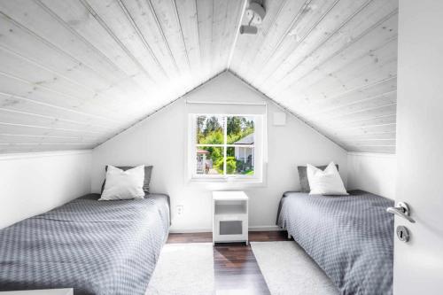 two beds in a room with a window at Coastal gem with beach, wooden sauna & canoes in Bjästa
