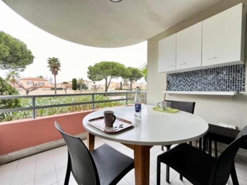 Cette chambre dispose d'un balcon avec une table et des chaises blanches. dans l'établissement Résidence Le Beaulieu - Appartement 6 couchages à Port Camargue MAE-5351, au Grau-du-Roi