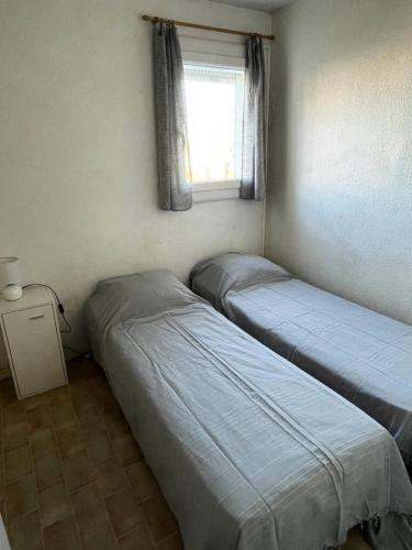deux lits dans une petite pièce avec une fenêtre dans l'établissement Résidence Les Caraibes - T2 dans résidence avec piscine MAE-5411, au Grau-du-Roi