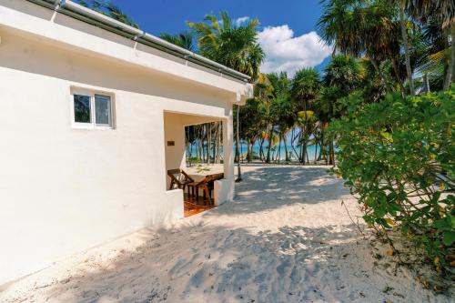 a house on the beach with a table and chairs at Hotel Cielo y Selva in Punta Allen