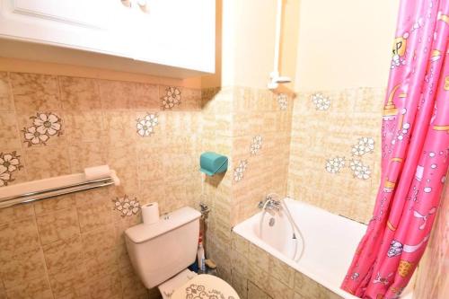 La salle de bains est pourvue de toilettes et d'un rideau de douche rose. dans l'établissement Résidence La Croisière - Studio cabine Croisière à Port Camargue MAE-5431, au Grau-du-Roi