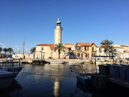 un bâtiment avec une tour d'horloge et des bateaux dans un port dans l'établissement Résidence La Croisière - Studio cabine Croisière à Port Camargue MAE-5431, au Grau-du-Roi