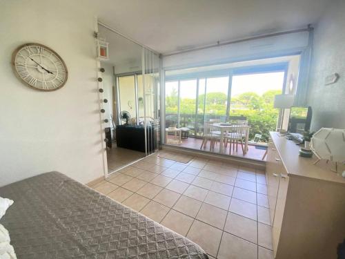 Cette chambre comprend un lit et une horloge murale. dans l'établissement Résidence Les Jardins Du Port - Superbe T2 en rez de jardin dans résidence avec piscine MAE-7031, au Grau-du-Roi