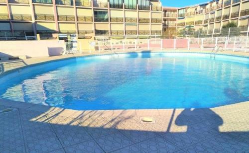 une grande piscine devant un immeuble dans l'établissement Résidence Le Lagon Bleu - Studio cabine 4 couchages avec piscine MAE-7111, au Grau-du-Roi