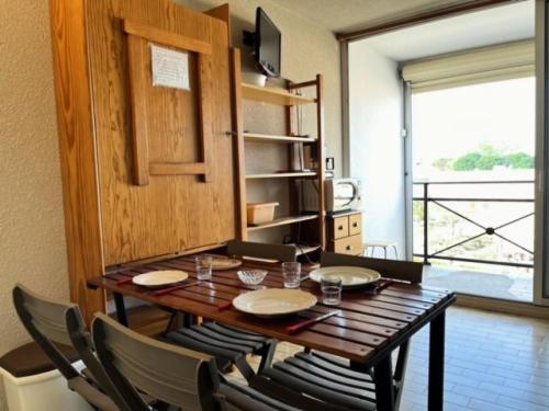 une salle à manger avec une table et des chaises en bois dans l'établissement Résidence Le Lagon Bleu - Studio cabine dans résidence avec piscine MAE-7131, au Grau-du-Roi