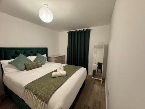 a bedroom with a large bed with a green headboard at Town centre 1 Cozy king size bed ensuit shower in Huntingdon