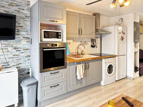 une cuisine avec des armoires blanches et un réfrigérateur blanc dans l'établissement Résidence Le Lagon Bleu - Studio 4 couchages dans residence avec piscine MAE-7201, au Grau-du-Roi