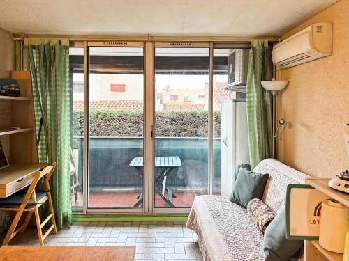 un salon avec un canapé et une porte coulissante en verre dans l'établissement Résidence Le Lagon Bleu - Studio dans résidence avec piscine MAE-7241, au Grau-du-Roi