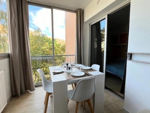 - une table et des chaises blanches dans une chambre dotée d'une grande fenêtre dans l'établissement Résidence Port Royal - Appartement 6 couchages au centre du Grau du roi MAE-9831, au Grau-du-Roi