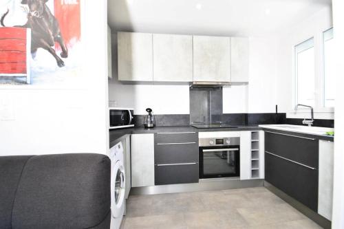 une cuisine avec des armoires blanches et un four à plaques de cuisson dans l'établissement Résidence Les Suzannes - Superbe T3 au Grau du Roi MAE-9841, au Grau-du-Roi