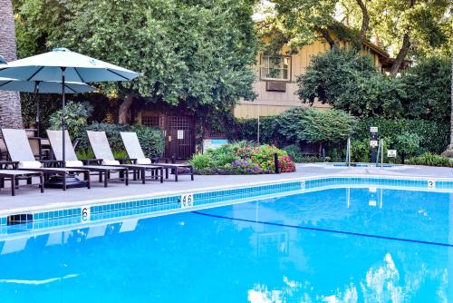 a swimming pool with lounge chairs and an umbrella at El Pueblo Inn in Sonoma