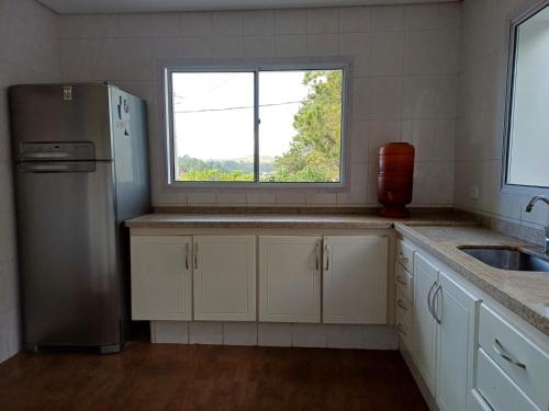 a kitchen with a stainless steel refrigerator and a window at Pôr do Sol da Bel in Campos do Jordão