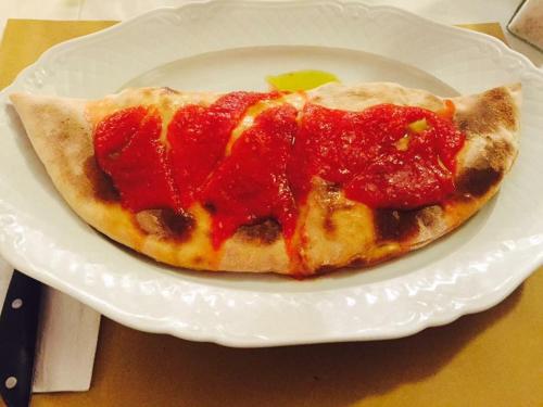 a pizza on a white plate on a table at Hotel Piero Della Francesca in Arezzo