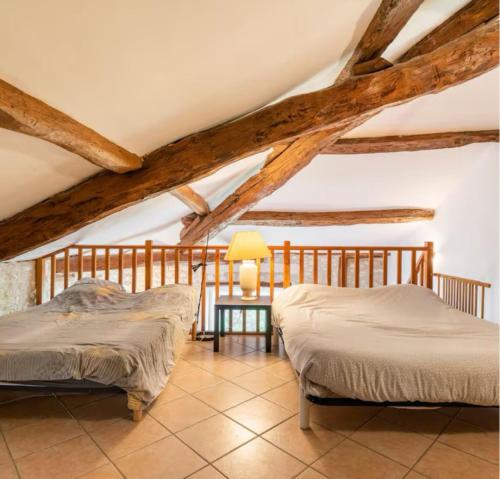 two beds in a room with wooden beams at Gîte de Lafargue - maison en pierre lumineuse in Cazes-Mondenard