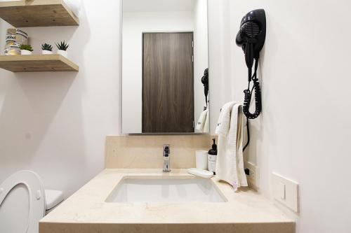 a bathroom with a sink with a phone on the wall at Tribu Chapultepec 67 in Guadalajara