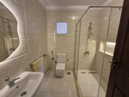 a bathroom with a toilet and a sink and a shower at Gardenia Comfort Haven Cozy & Spacious 3BR Getaway in Cairo