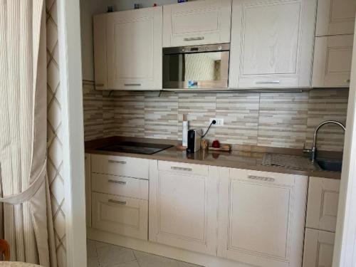 a kitchen with white cabinets and a microwave at Eden rock apartment in Grimaldi