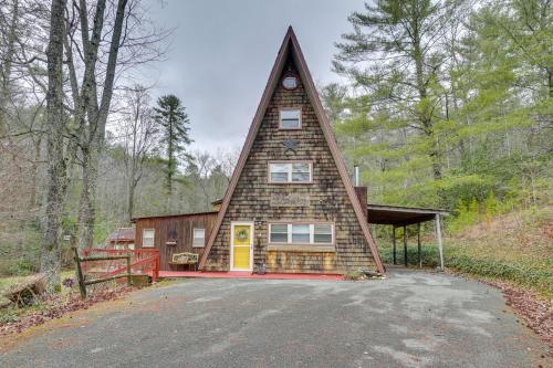 a house with a steep roof in the woods at A-Frame Cabin with Spacious Yard in Tellico Plains! in Tellico Plains