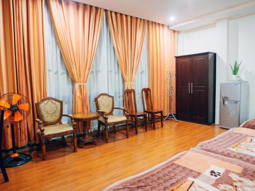 a bedroom with two beds and a table and chairs at Huỳnh Gia Bảo Hotel in Bao Loc