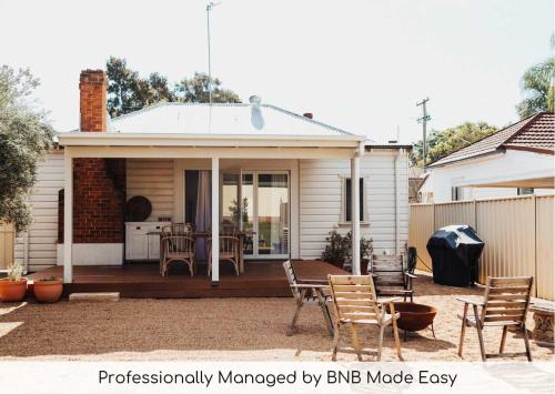 a house with a deck with a table and chairs at Olive Cottage - CBD Location, Pet friendly in Dubbo