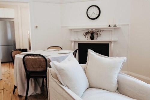 a living room with a couch and a clock on the wall at Olive Cottage - CBD Location, Pet friendly in Dubbo