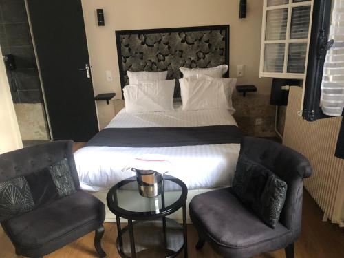une chambre avec un lit avec deux chaises et une table dans l'établissement Jardin Abbatiale, à Rouen