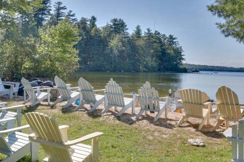 a row of chairs sitting on the shore of a lake at The Birches Raymond Getaway with Beach and Boat Dock in Raymond