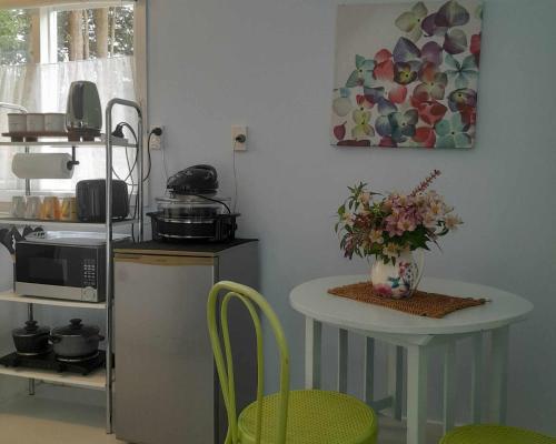 a kitchen with a table with a vase of flowers on it at La Petite Ferme Studio Kerikeri in Kerikeri