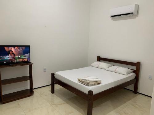 a bedroom with a bed and a tv in a room at Chalés de Morro Branco in Beberibe