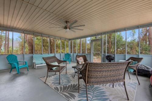 a screened in porch with chairs and a ceiling fan at Gulf Brz-Beaches-Dwntwn PNS-Pet Friendly-Canal in Gulf Breeze