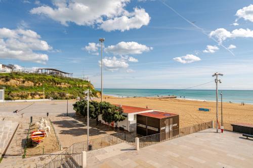 a beach with a building and the ocean at Down Town Beach House in Albufeira