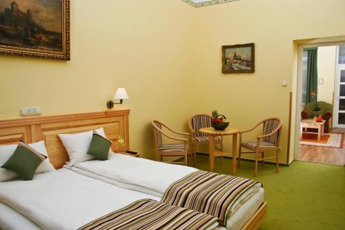 a bedroom with a bed and a table with chairs at Hotel Manzard Panzio in Budapest