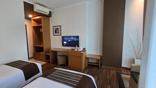 a hotel room with a bed and a desk with a television at Point C Hotel in Bandung